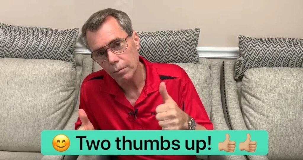 A man wearing a red polo doing a thumbs up